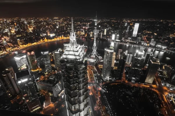 Aerial view of Shanghai at night, with the Jin Mao Tower and Oriental Pearl Tower beside the Huangpu River and the lit-up Bund on the far bank