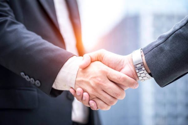 Close-up of two business professionals shaking hands in a formal setting