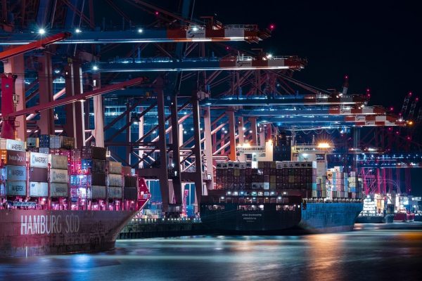 A busy shipping port at night with large cranes and cargo ships