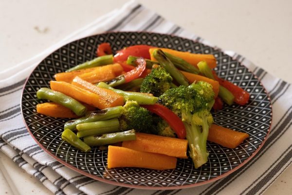 A colorful plate of cooked vegetables including broccoli, carrots, and green beans.