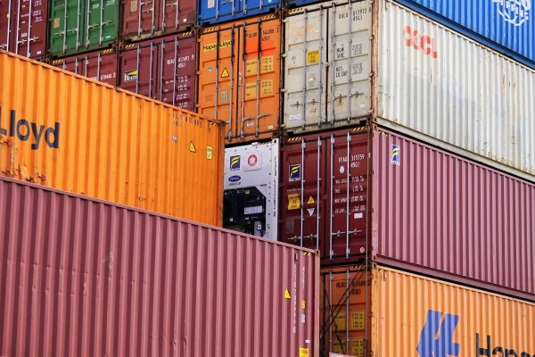 Shipping containers stacked at a port illustrating the tariff impact on global sourcing.