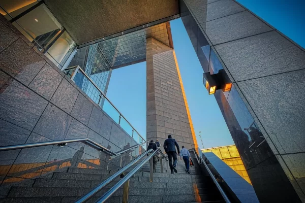 Corporate team ascending stairs to a modern office for buying office tactics strategy