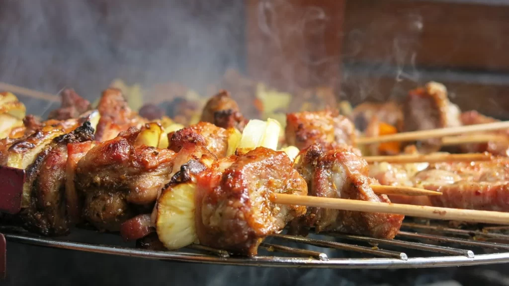Freshly grilled meat and vegetable BBQ skewers cooking over a charcoal grill.